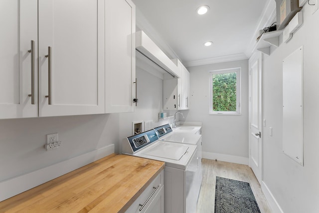 clothes washing area with cabinets, crown molding, sink, separate washer and dryer, and light hardwood / wood-style flooring