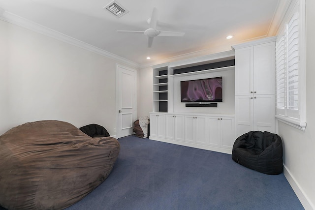 living area with built in shelves, ceiling fan, ornamental molding, and dark colored carpet