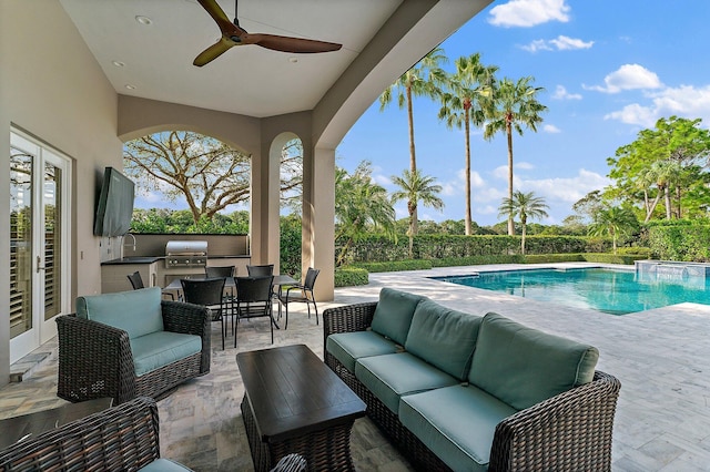 view of swimming pool featuring outdoor lounge area, ceiling fan, a grill, a patio area, and exterior kitchen