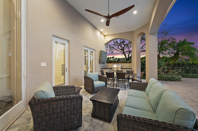 patio terrace at dusk with a grill, ceiling fan, and an outdoor living space