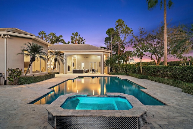 pool at dusk featuring an in ground hot tub, an outdoor living space, a patio, and ceiling fan