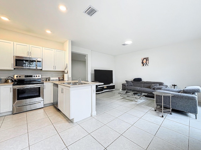 kitchen with stainless steel appliances, white cabinetry, sink, kitchen peninsula, and light tile patterned floors