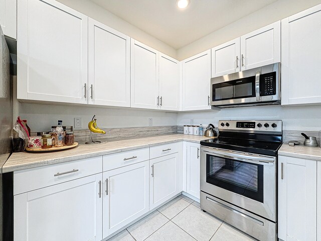 kitchen with white cabinets, light tile patterned floors, and stainless steel appliances