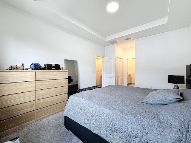 bedroom with ensuite bath, carpet flooring, and a raised ceiling