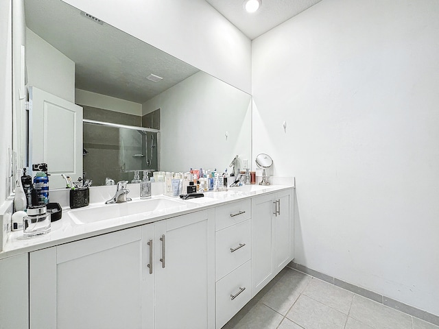 bathroom with an enclosed shower, vanity, a textured ceiling, and tile patterned flooring