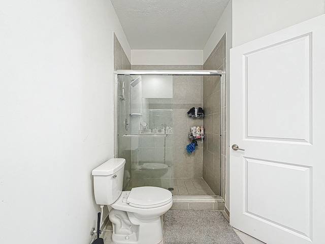 bathroom with toilet, an enclosed shower, and a textured ceiling