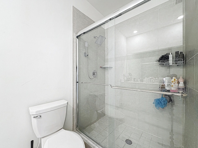 bathroom featuring a shower with door and toilet