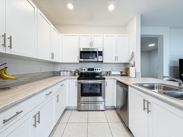 kitchen with white cabinets, light tile patterned floors, sink, and appliances with stainless steel finishes