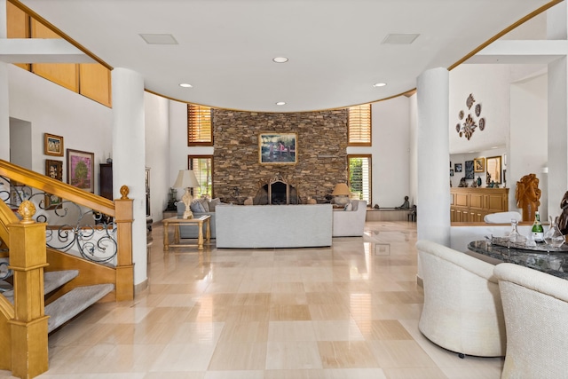 tiled living room with a stone fireplace and a towering ceiling