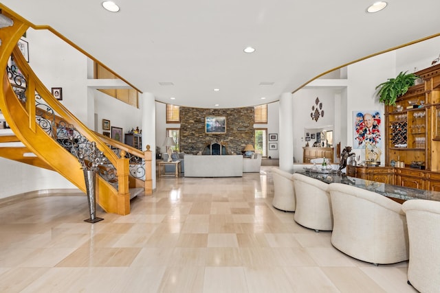 tiled living room featuring a stone fireplace and a towering ceiling