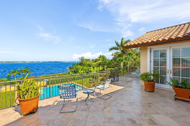 view of patio / terrace featuring a water view, a fenced in pool, and french doors