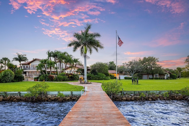 view of dock with a lawn and a water view