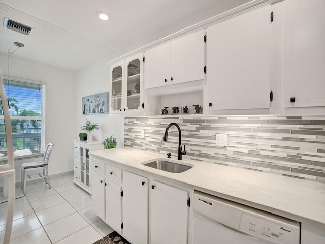 kitchen with dishwasher, backsplash, white cabinets, sink, and light tile patterned floors