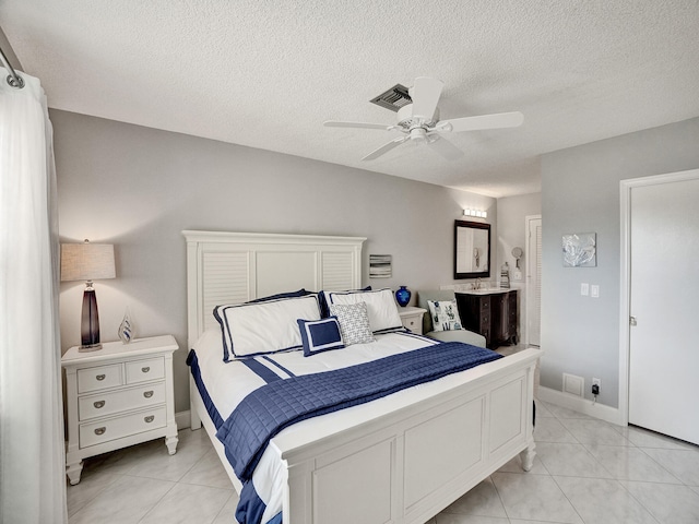 bedroom featuring ceiling fan, light tile patterned floors, and a textured ceiling