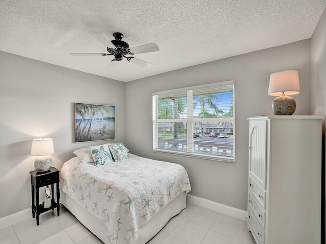 bedroom with ceiling fan, light tile patterned flooring, and a textured ceiling