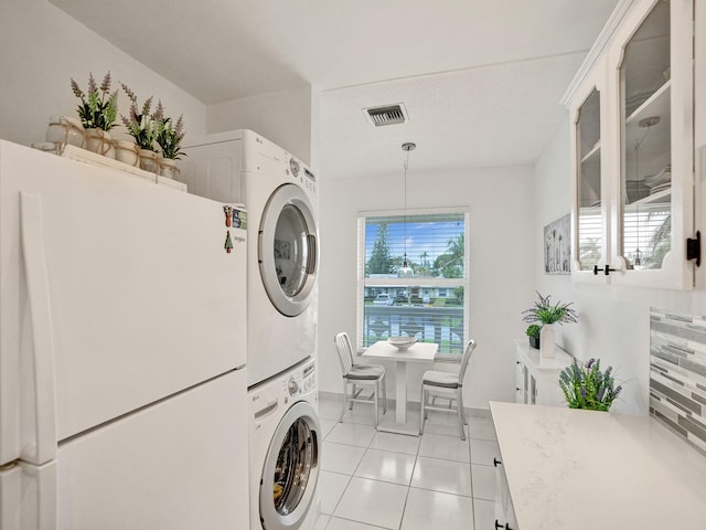 laundry room featuring stacked washer and dryer and light tile patterned flooring