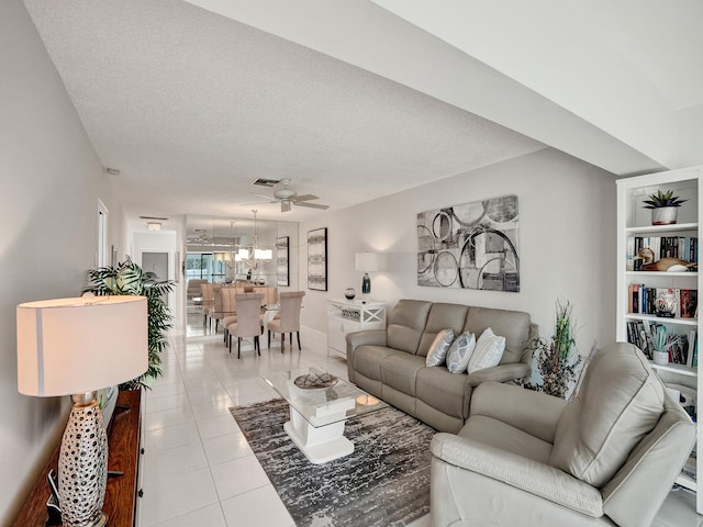 living room featuring ceiling fan, light tile patterned flooring, and a textured ceiling