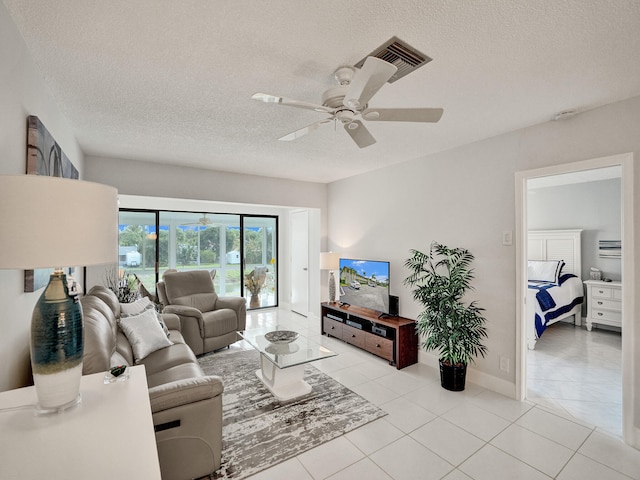 living room featuring ceiling fan, light tile patterned floors, and a textured ceiling