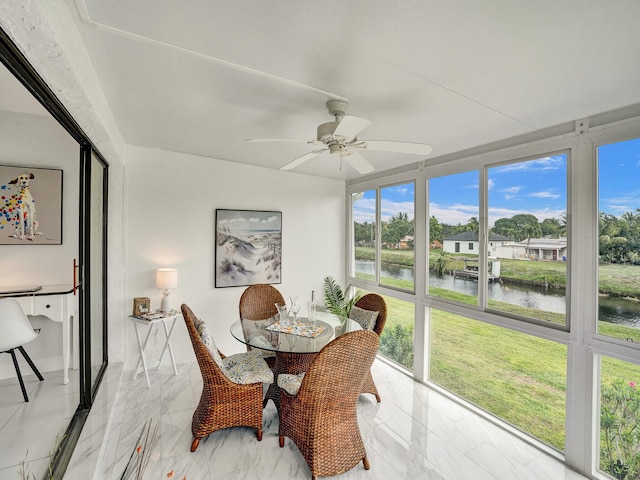 sunroom featuring ceiling fan, a healthy amount of sunlight, and a water view