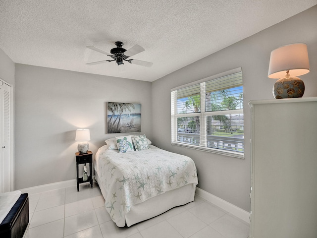 tiled bedroom with a textured ceiling, a closet, and ceiling fan