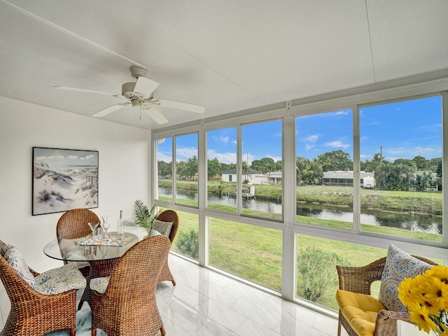 sunroom featuring ceiling fan and a water view