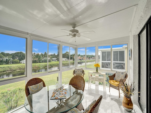 sunroom / solarium with ceiling fan and a water view