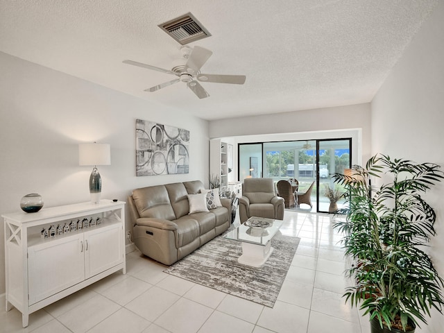 living room with a textured ceiling, ceiling fan, and light tile patterned flooring