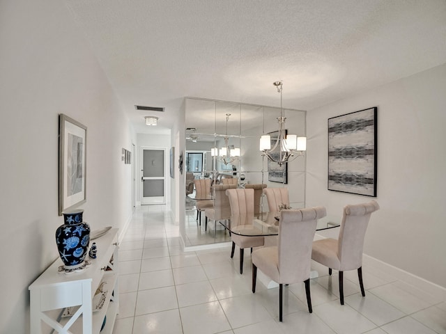 tiled dining area with a textured ceiling and ceiling fan with notable chandelier