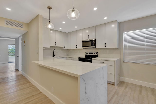 kitchen featuring stainless steel appliances, light hardwood / wood-style floors, sink, light stone countertops, and pendant lighting