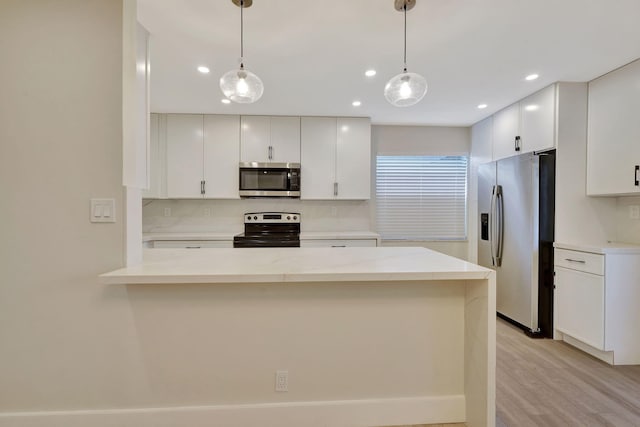 kitchen with stainless steel appliances, pendant lighting, white cabinets, and a peninsula