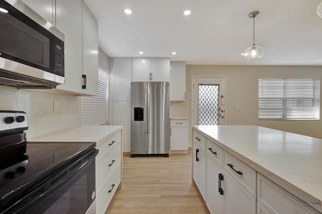 kitchen with white cabinets, appliances with stainless steel finishes, backsplash, light wood finished floors, and decorative light fixtures