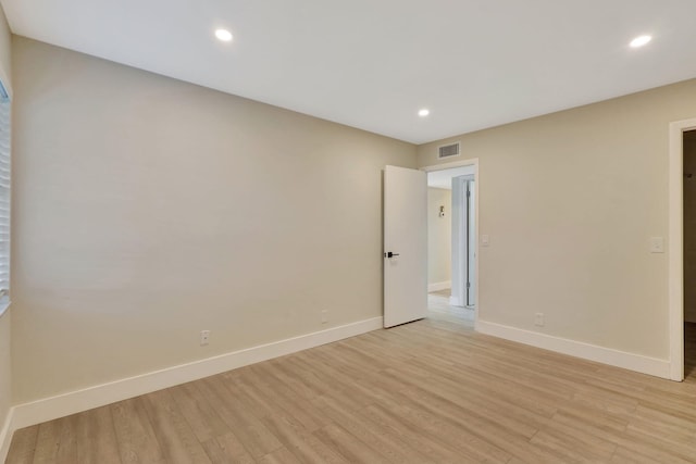 spare room with light wood-type flooring, visible vents, and baseboards