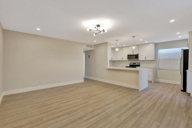 kitchen featuring stainless steel appliances, pendant lighting, white cabinets, kitchen peninsula, and light hardwood / wood-style flooring