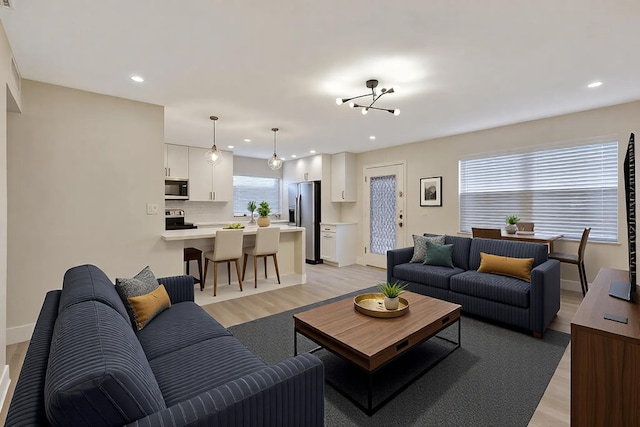 living room featuring light wood-style floors, recessed lighting, a notable chandelier, and baseboards