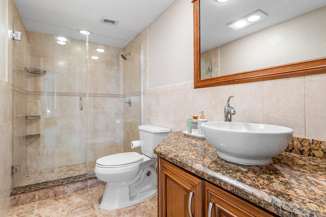 bathroom featuring vanity, toilet, tile walls, and a shower with shower door