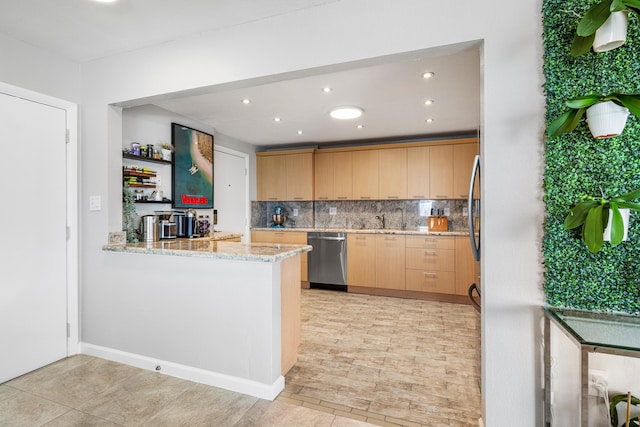 kitchen featuring kitchen peninsula, backsplash, stainless steel dishwasher, light brown cabinetry, and light stone counters