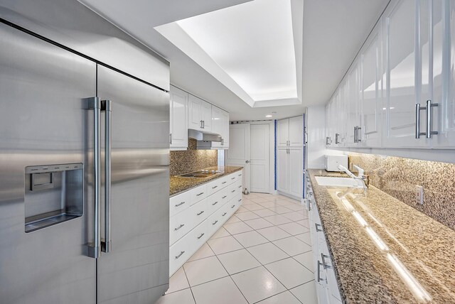 kitchen with tasteful backsplash, white appliances, white cabinets, and dark stone countertops