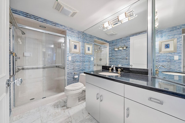 bathroom with vanity, toilet, a shower with door, and tile walls