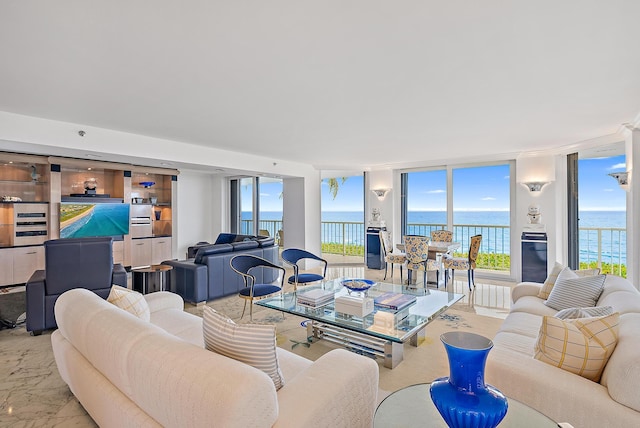 living area featuring expansive windows, marble finish floor, beverage cooler, and a water view