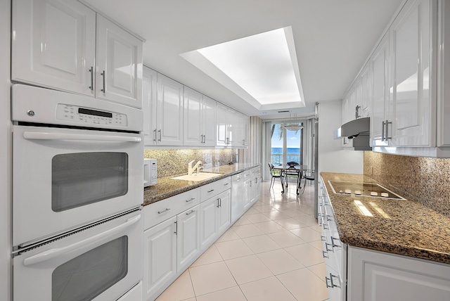 kitchen with white cabinets, white appliances, sink, and dark stone countertops