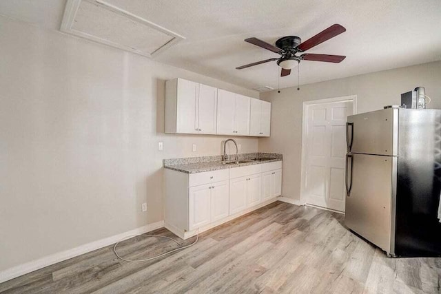 2511 W Abdella St, Tampa, FL 33607 - kitchen with sink, light stone countertops, stainless steel fridge, white cabinets, and light hardwood / wood-style floors