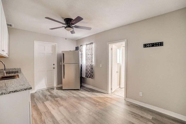 2511 W Abdella St, Tampa, FL 33607 - kitchen featuring sink, light wood-type flooring, stainless steel fridge, ceiling fan, and white cabinets