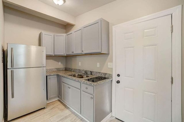 2511 W Abdella St, Tampa, FL 33607 - kitchen featuring light stone counters, stainless steel refrigerator, light hardwood / wood-style flooring, gray cabinets, and sink