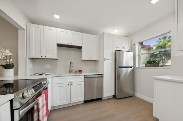 kitchen with sink, white cabinetry, light hardwood / wood-style flooring, and stainless steel appliances