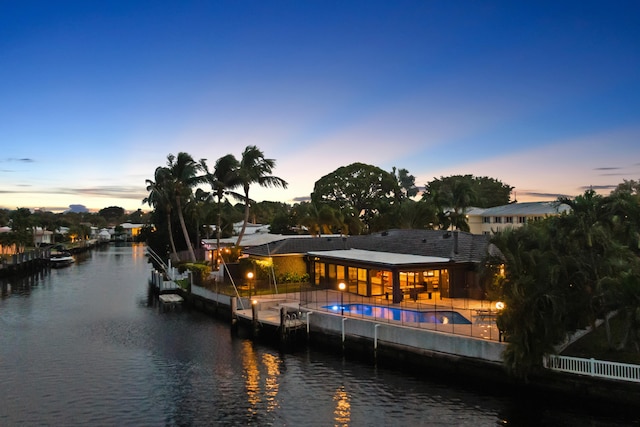 back house at dusk with a water view and a patio area