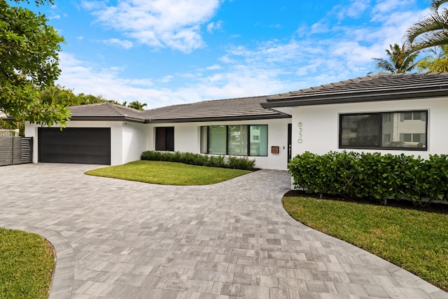 single story home with a garage and a front lawn