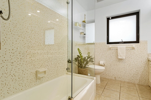 bathroom with tile walls, tiled shower / bath combo, tile patterned floors, and toilet