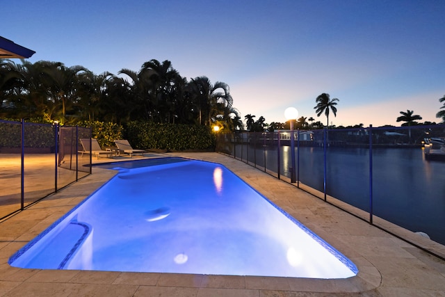 pool at dusk with a patio and a water view