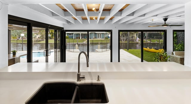 interior space featuring beamed ceiling, a water view, sink, and wood ceiling