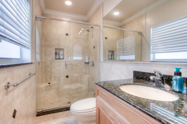 bathroom featuring toilet, a shower with shower door, vanity, crown molding, and tile walls